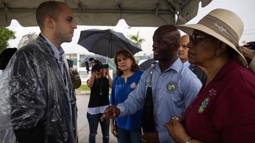 La representante estatal Kionne McGhee y la comisionada del condado de Miami-Dade, Barbara Jordan, hablan con un funcionario de la instalación de Homestead que alberga a niños inmigrantes separados de sus padres. 