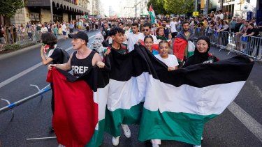 Manifestantes propalestinos sostienen una bandera del país luego de que invadieran las calles durante la Vuelta a España, el 14 de septiembre de 2025.