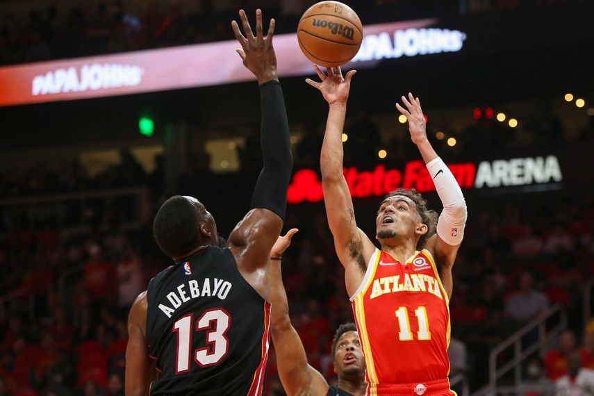 El base de los Hawks de Atlanta Trae Young lanza el balón entre el pívot Bam Adebayo y el base Kyle Lowry del Heat de Miami en el encuentro de la primera ronda de la postemporada del viernes 22 de abril del 2022 en Atlanta.&nbsp;