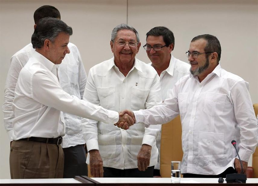 El presidente de Colombia Juan Manuel Santos (i) y el máximo líder de las FARC, Rodrigo Londoño (2d), alias Timochenko, se dan la mano junto al presidente de Cuba Raúl Castro, tras anunciar en La Habana el acuerdo alcanzado entre las partes en materi