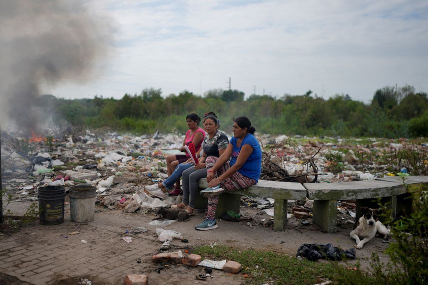 Las mujeres se sientan en un banco en un predio donde se tira la basura, cerca de sus casas, en Tucumán, Argentina, el jueves 30 de marzo de 2023.&nbsp;