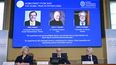 El secretario general de la Real Academia Sueca de Ciencias, Hans Ellegren, en el centro, y los miembros del Comité del Nobel para Física, Eva Olsson, a la izquierda, y Thors Hans Hansson, a la derecha, anuncian a los ganadores del Nobel de Física de 2022, de izquierda a derecha en la pantalla Alain Aspect, John F. Clauser y Anton Zeilinger, en una conferencia de prensa de la Academia en Estocolmo, Suecia, el martes 4 de octubre de 2022.