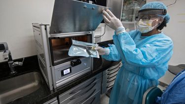 Un asistente de dentista sostiene utensilios desinfectados en la m&aacute;quina SIWA N95 desarrollada por la empresa costarricense Plasma Innova y el Instituto Tecnol&oacute;gico de Costa Rica (TEC) en San Jos&eacute;, el 22 de julio de 2020.