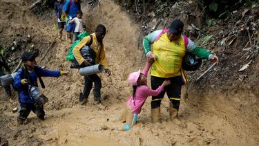 &nbsp;Una mujer trata de levantar a una niña de un paso enlodado mientras migrantes ecuatorianos atraviesan la selva del Darién para llegar desde Colombia a Panamá en su ruta hacia Estados Unidos, el 15 de octubre de 2022