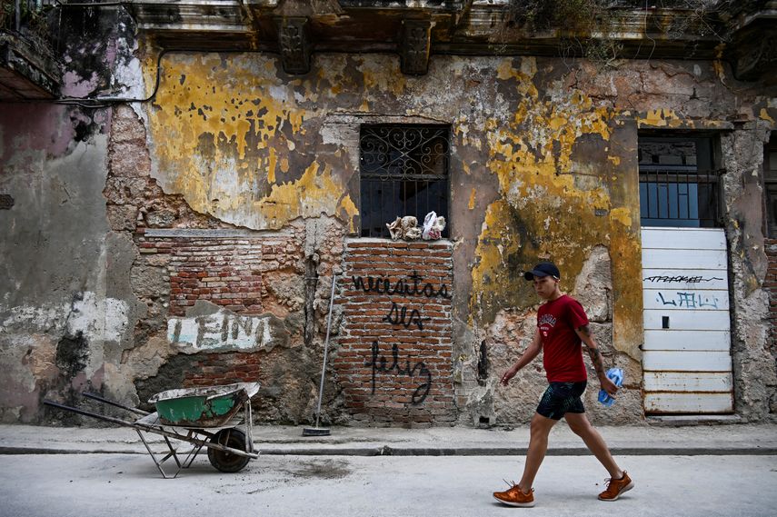 Un hombre pasa junto a un graffiti que dice Necesitas ser feliz del artista cubano Mr. Sad en La Habana, el 12 de diciembre de 2024.