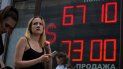 Una mujer camina junto a una pantalla que muestra el tipo de cambio del dólar estadounidense frente al rublo ruso, en San Petersburgo, Rusia. 