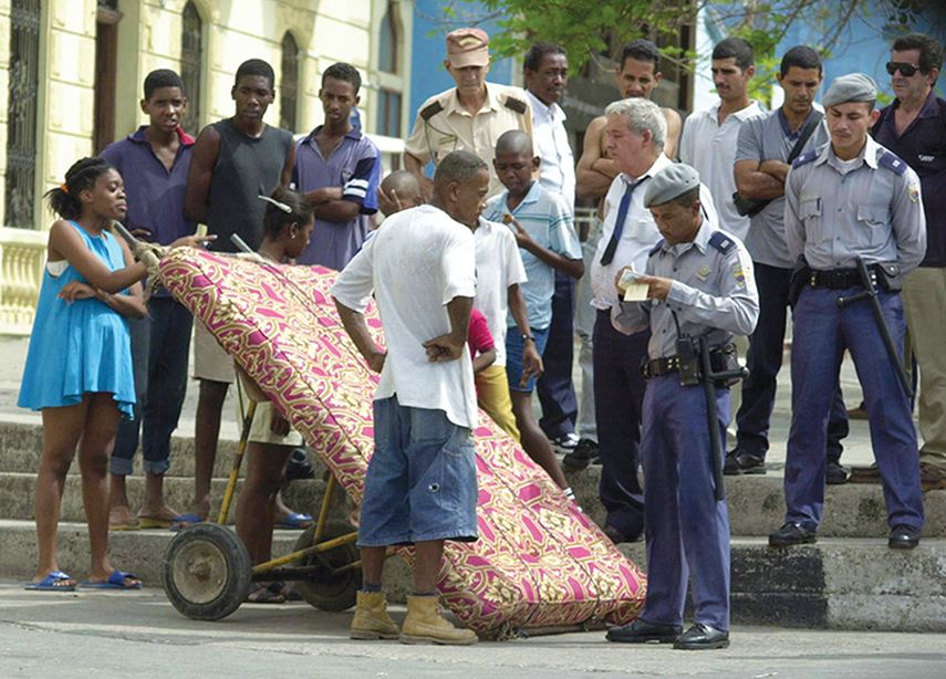 Policías cubanos identifican a un ciudadano que transporta un colchón, en la zona de La Habana Vieja (EFE)