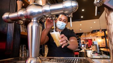 Un empleado sirve una vaso de cerveza en un restaurante.