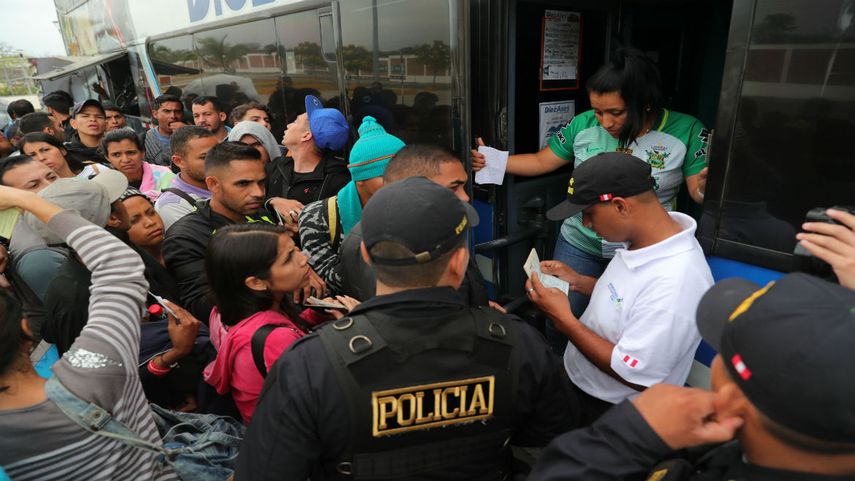 Inmigrantes venezolanos presentan sus documentos al subir a un bus que los llevará a Trujillo, Perú.