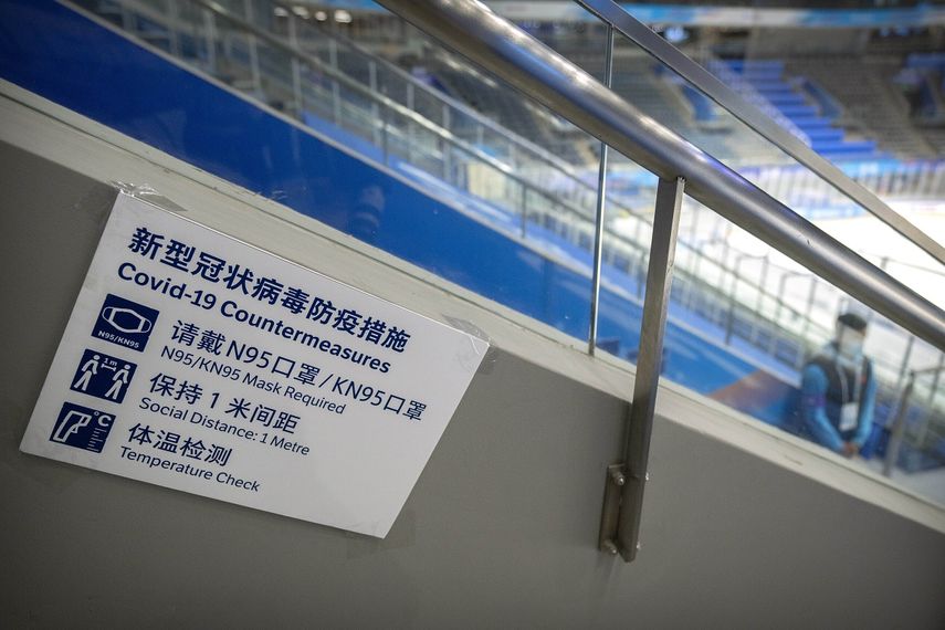 En esta imagen de archivo, un miembro del equipo, junto a un cartel con las normas de protección contra el COVID-19, durante la celebración del evento de prueba de hockey sobre hielo previo a los Juegos Olímpicos de Invierno de Beijing 2022, en el Estadio Nacional Indoor, en Beijing, el 10 de noviembre de 2021.&nbsp;
