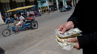 Una persona muestra dólares estadounidenses frente a un banco en La Habana, Cuba. 