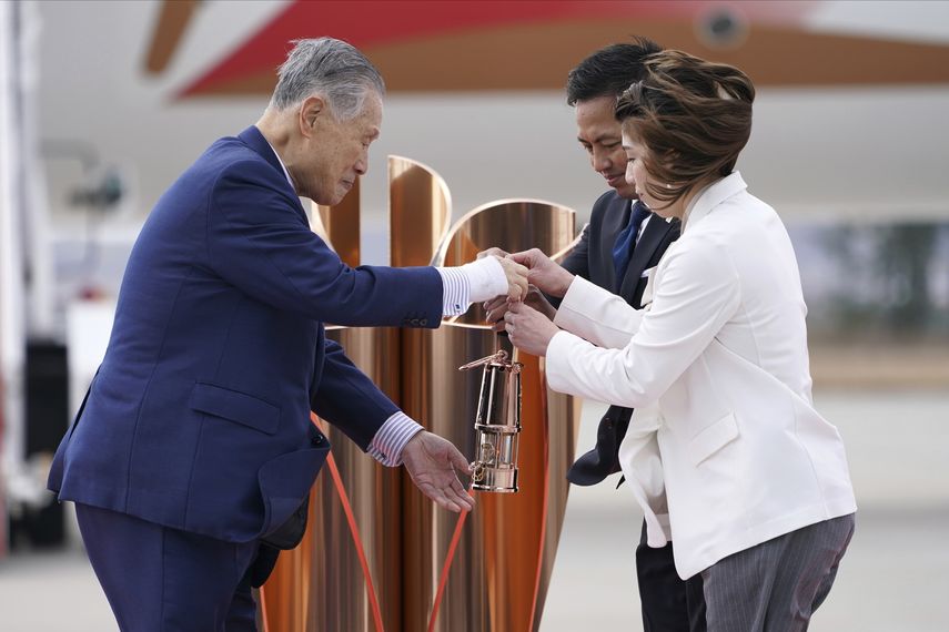 Yoshiro Mori (izquierda), jefe del comit&eacute; organizador de los Juegos Ol&iacute;mpicos de Tokio, recibe la llama ol&iacute;mpica de manos de los medallistas de oro Tadahiro Nomura y Saori Yoshida, durante una ceremonia realizada en la Base A&eacute;rea de Matsushima, el viernes 20 de marzo de 2020