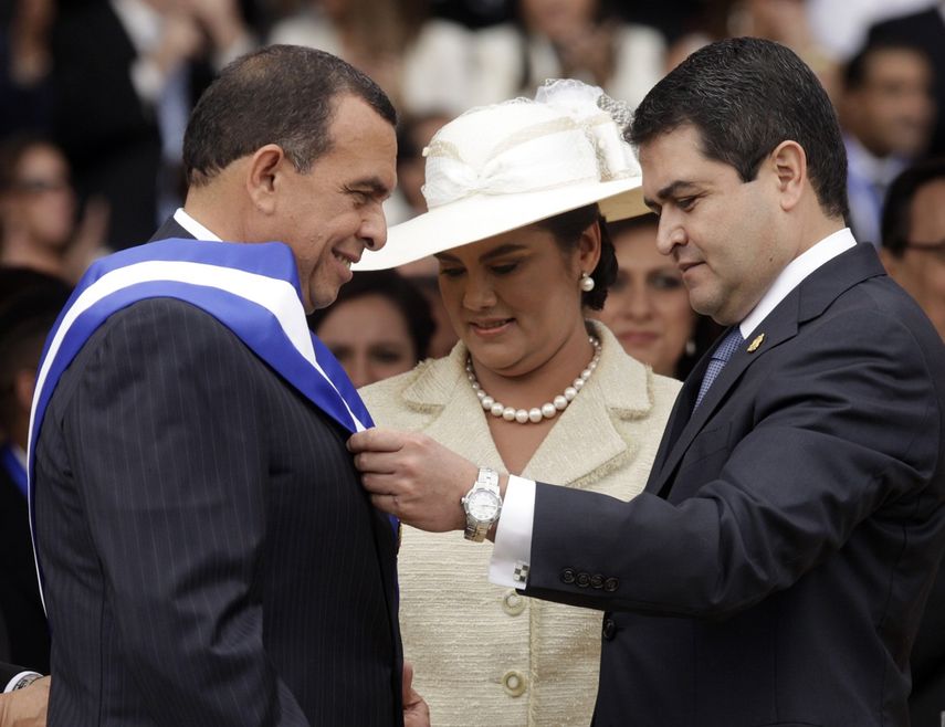En esta foto del 27 de enero de 2010, Juan Orlando Hernandez, presidente del Congreso y actual mandatario, coloca la banda presidencial a Porfirio Lobo durante una ceremonia en Tegucigalpa, Honduras.