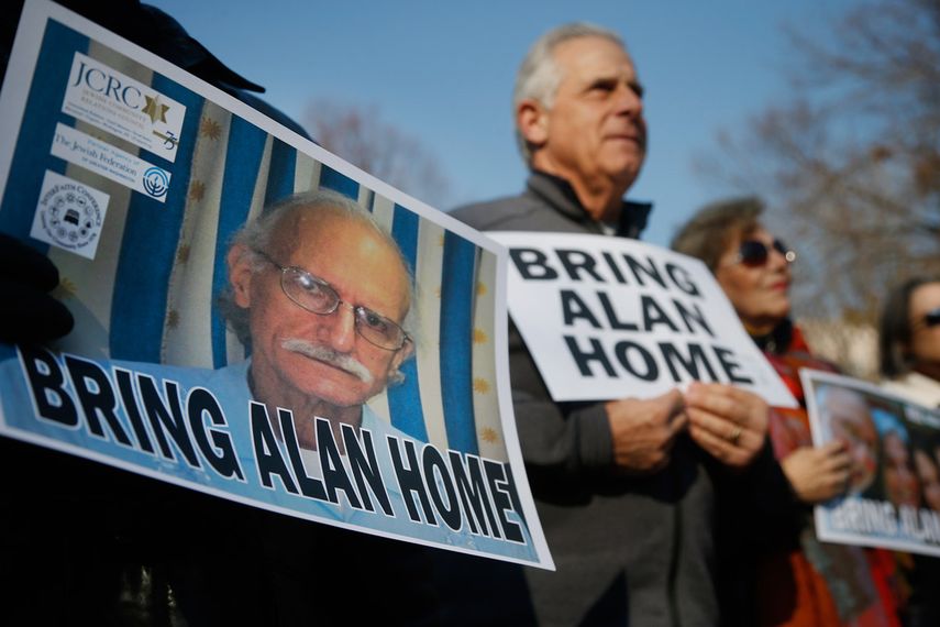 En esta foto del 3 de diciembre de 2013, partidarios de Alan Gross (cuyo rostro se muestra en un poster a la izquierda) conmemoran el cuarto aniversario de su arresto en Cuba con una protesta en el Parque Lafayette Park, frente a la Casa Blanca en Wash