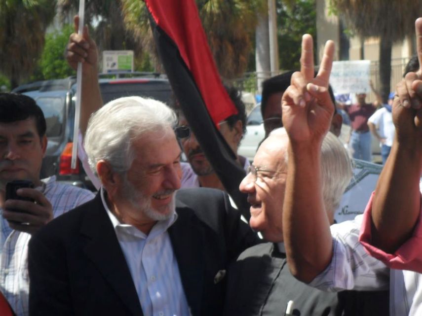El entonces canciller del régimen de Daniel Ortega, Samuel Santos, durante una actividad política del FSLN en el Consulado de Nicaragua en Miami, junto al sacerdote de origen cubano Eduardo de Zayas, presidente de la fundación Compañeros de Jesús de Nazareth en Miami, en 2011.