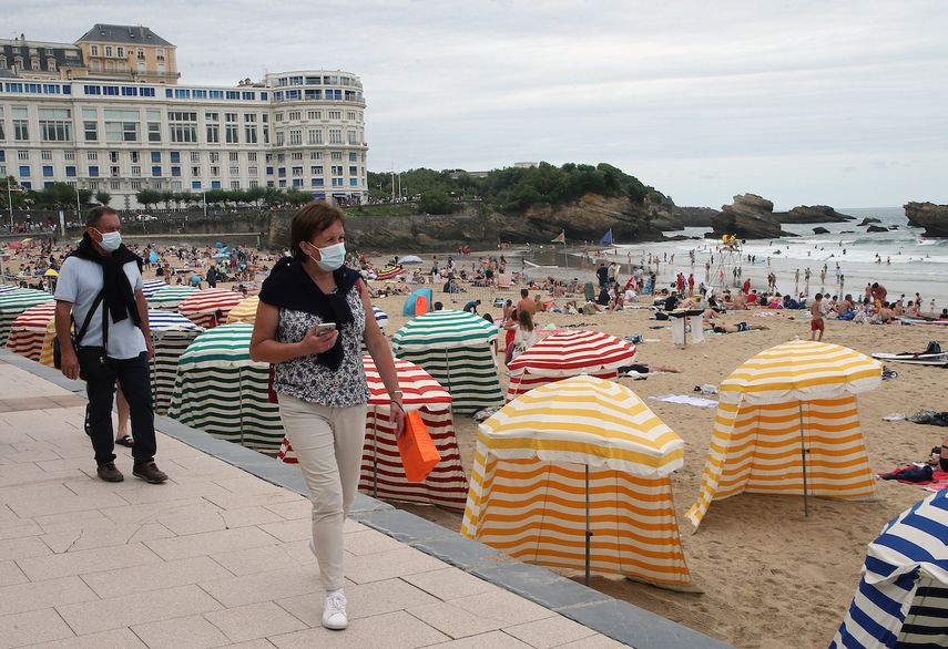 En esta fotografía de archivo del miércoles 28 de julio de 2021, dos personas que portan mascarillas para protegerse del coronavirus caminan junto a la playa en Biarritz, en el suroeste de Francia.&nbsp;