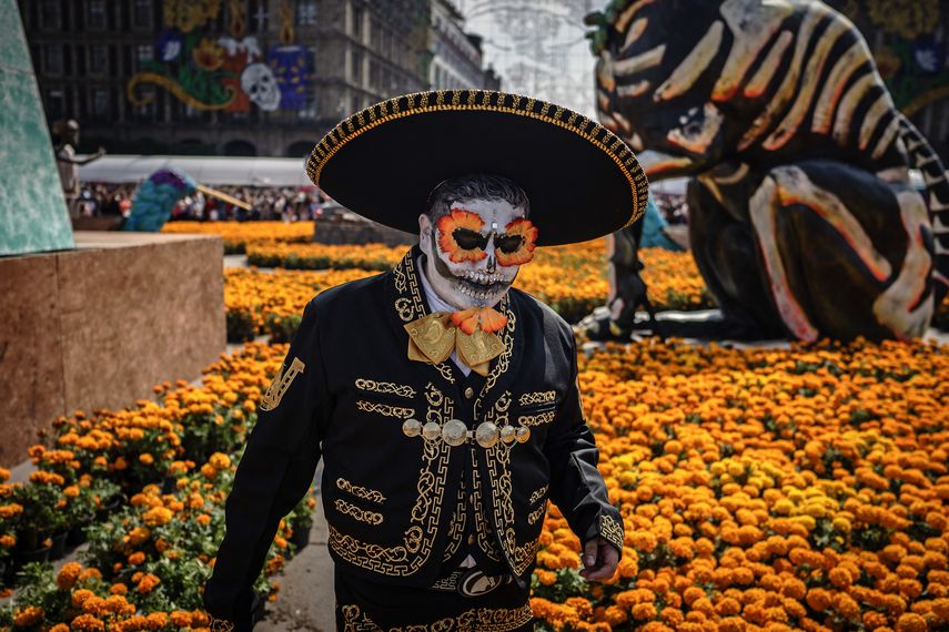 Un hombre disfrazado pasa junto a cempasúchiles durante las celebraciones anuales del Día de Muertos en la Ciudad de México el 2 de noviembre de 2025.