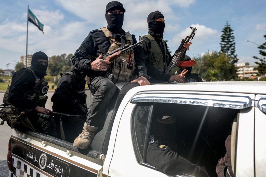 Las fuerzas de seguridad leales al gobierno interino sirio viajan en la parte trasera de un vehículo que circula por una carretera en la ciudad de Latakia, en el oeste de Siria, el 9 de marzo de 2025.