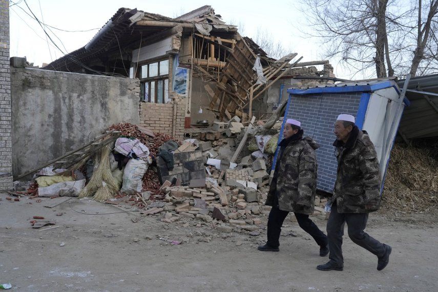 Residentes caminan el miércoles 20 de diciembre de 2023 frente a una vivienda colapsada tras un sismo en la localidad de Yangwa, en la provincia de Gansú, China.&nbsp;