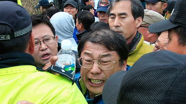 Parientes de los pasajeros desaparecidos en un transbordador hundido forcejean con policías mientras intentan llegar a la casa presidencial para protestar por las operaciones de rescate implementadas por el gobierno en un puerto en Jindo, Corea del Sur