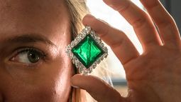 Una empleada de Christies posa con The Aga Khan Emerald, un broche de Cartier con esmeraldas y diamantes elaborado con una esmeralda cuadrada de 37,00 quilates, diamantes en forma de marquesa, platino y oro amarillo de 18 quilates durante una presentación de prensa en Ginebra, el 7 de noviembre de 2024.  