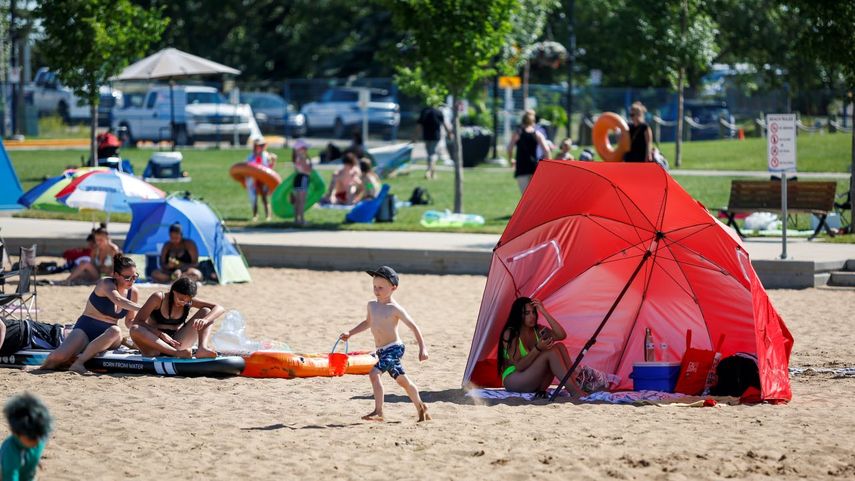 Varias personas disfrutan del calor en una playa.