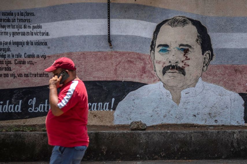 Un hombre camina junto a un estropeado mural del dictador de Nicaragua, Daniel Ortega, en Managua el 14 de abril de 2020.