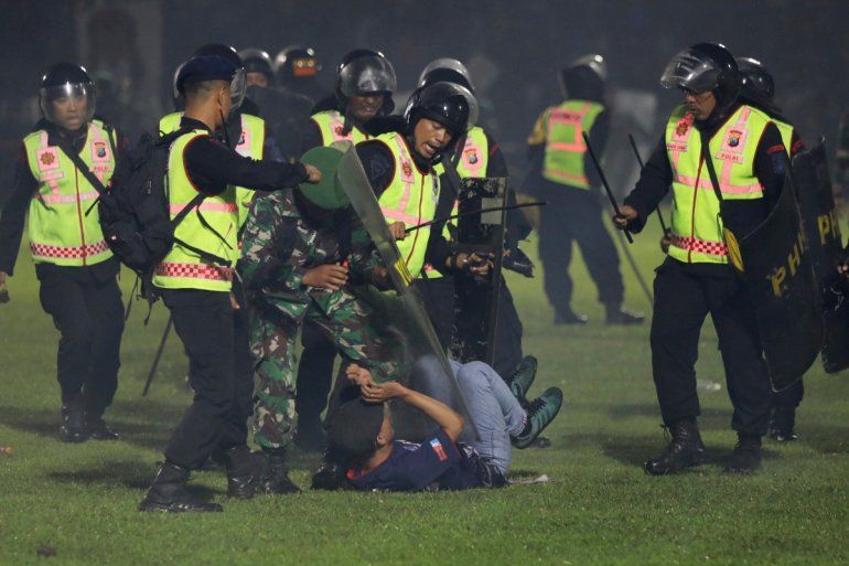 Agentes de seguridad detienen a un aficionado durante una serie de trifulcas en un partido de fútbol, el sábado 1 de octubre de 2022, en Malang, Indonesia 