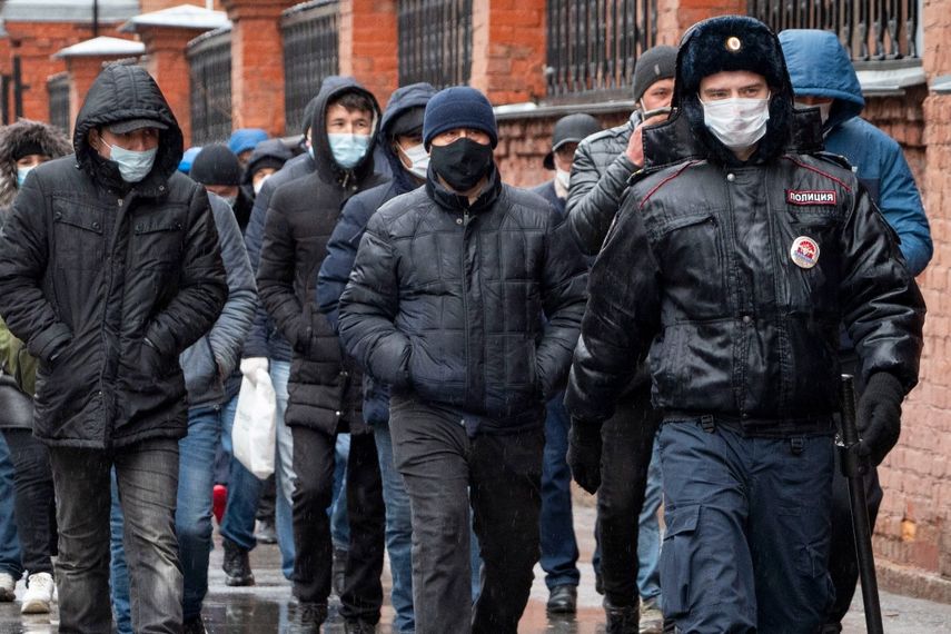 ARCHIVO - En esta fotografía del 2 de abril de 2020, unos agentes de la policía acompañan a un grupo de migrantes, en San Petersburgo, Rusia. La ONU había proyectado que la migración internacional crecería entre 7 y 8 millones para mediados de 2019 y mediados de 2020.