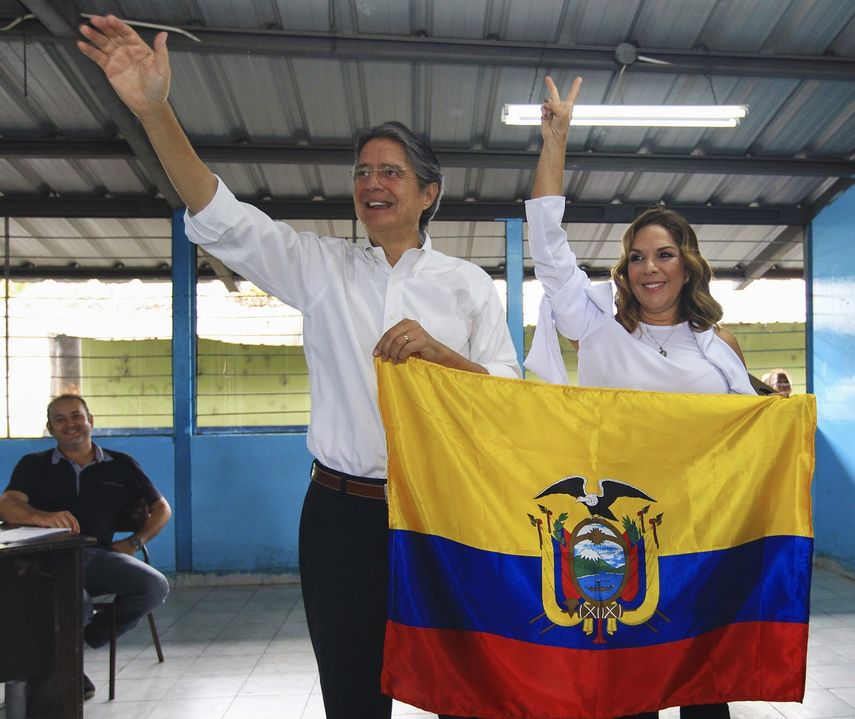El candidato opositor a la Presidencia de Ecuador, Guillermo&nbsp;Lasso&nbsp;(i), acompañado de su esposa María de Lourdes Alcívar (d), sostiene la bandera ecuatoriana mientras saluda después de vota en Guayaquil (Ecuador).
