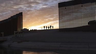 Un par de familias migrantes atraviesan un hueco en el muro fronterizo para llegar a Estados Unidos después de cruzar desde México en Yuma, Arizona.&nbsp;