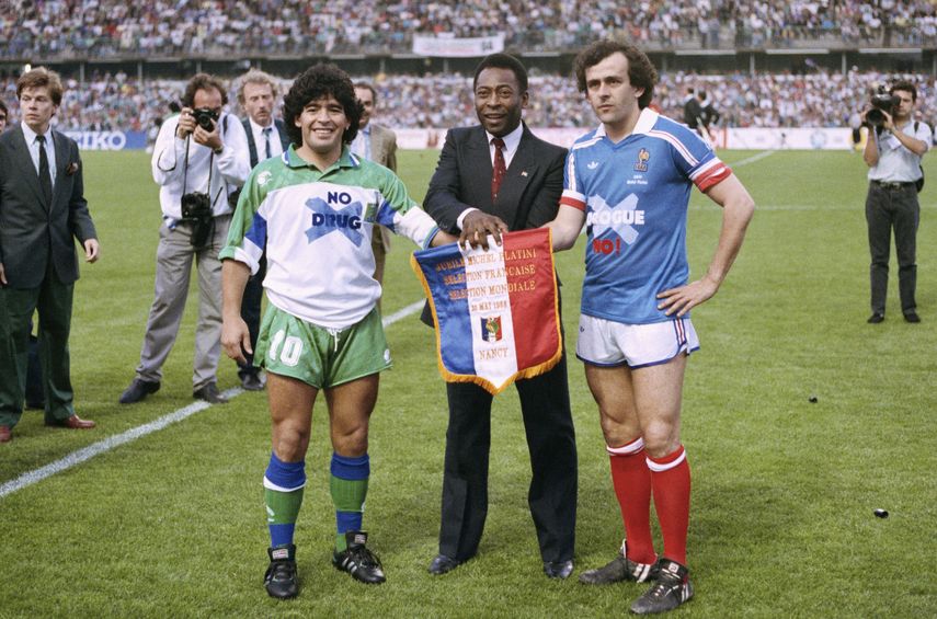 En imagen de archivo del 23 de mayo de 1998, el astro argentino Diego Armando Maradona, izquierda, el brasileño Pelé, centro, y el francés Michel Platini posan estrechando manos durante el partido de despedida de Platini en el estadio Nancy, en el este de Francia.&nbsp;