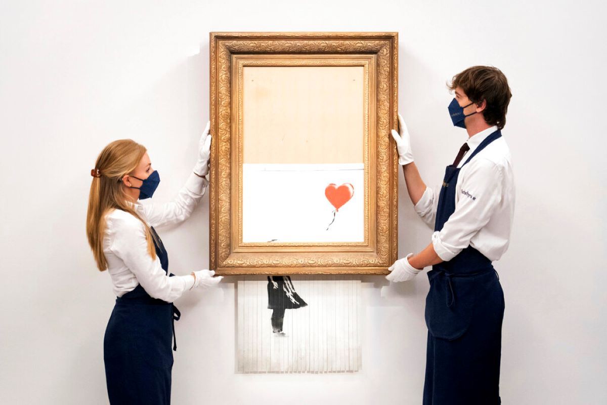 Manipuladores de arte sostienen Love is in the Bin de Banksy en la casa de subastas Sothebys en Londres. Manipuladores de arte sostienen Love is in the Bin de Banksy en la casa de subastas Sothebys en Londres.