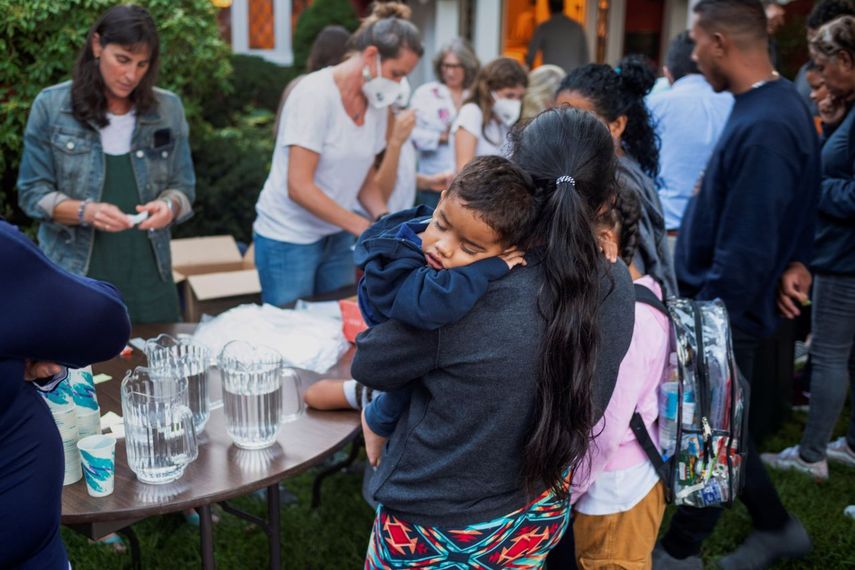 Una mujer, que está en un grupo de migrantes que fueron trasladados a Marthas Vineyard, Massachussets, carga a uno de sus hijos con los que llegó a EEUU, mientras reciben alimentos en una iglesia.&nbsp;