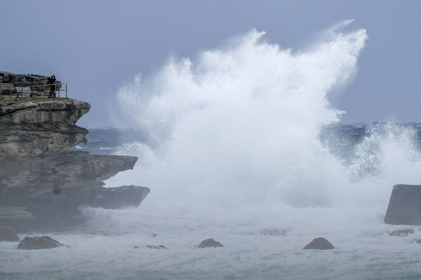 Gente al borde de un acantilado mientras las olas golpean la costa en Bondi Beach, Sydney, Australia, el domingo 3 de julio de 2022. Miles de vecinos en los suburbios de Sydney recibieron orden de evacuar el domingo después de que fuertes lluvias provocaran crecidas y desbordamientos, que las autoridades describieron como emergencias que ponían vidas en peligro.&nbsp;