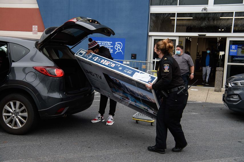 Un comprador es asistido para trasladar un televisor nuevo en su vehículo.