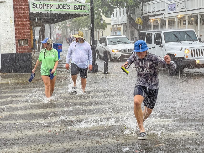 Florida: Peatones pasan por el cruce entre las calles Greene y Duval en medio de fuertes vientos y lluvias