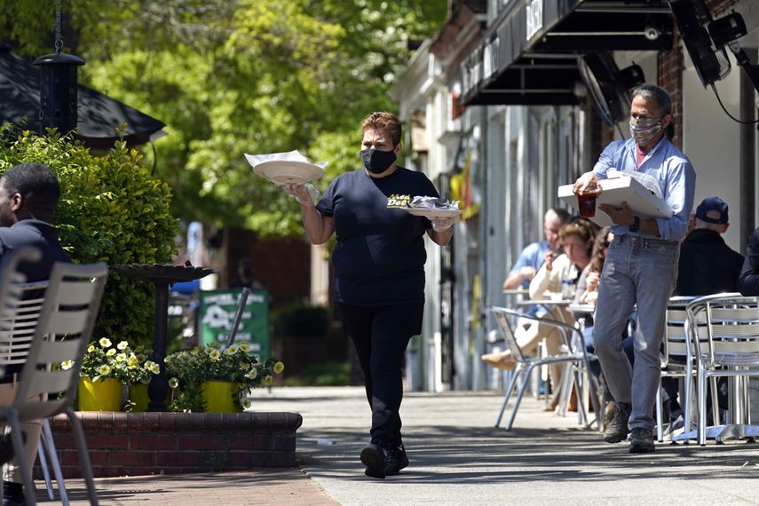Empleada de restaurante atiende a clientes en una terraza.