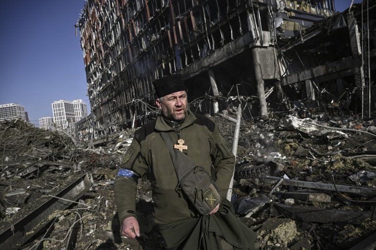 El capellán del ejército de Ucrania Mikola Madenski camina a través de los escombros fuera del destruido centro comercial Retroville en un distrito residencial, después de un ataque ruso en la capital de Ucrania, Kiev, el 21 de marzo de 2022.  