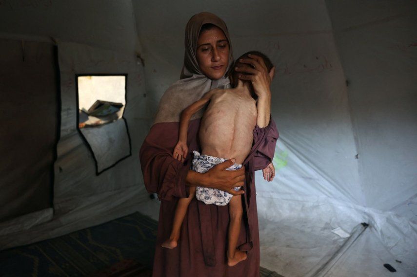 Hidaya, una madre palestina de 31 años, acuna a su hijo Mohammed al-Mutawaq, de 18 meses, enfermo y con síntomas de desnutrición, dentro de su tienda de campaña en el campo de refugiados de Al-Shati, al oeste de la ciudad de Gaza, el 24 de julio de 2025.&nbsp;