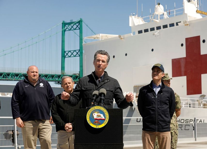 El gobernador de California, Gavin Newsom, al centro, pronuncia un mensaje frente al buque hospital Mercy de la Armada que llegó al puerto de Los Ángeles, el viernes 27 de marzo de 2020, para recibir a pacientes no infectados y liberar camas en hospitales que atenderán a personas contagiadas del coronavirus. A la derecha, el alcalde de Los Ángeles, Eric Garcetti. 