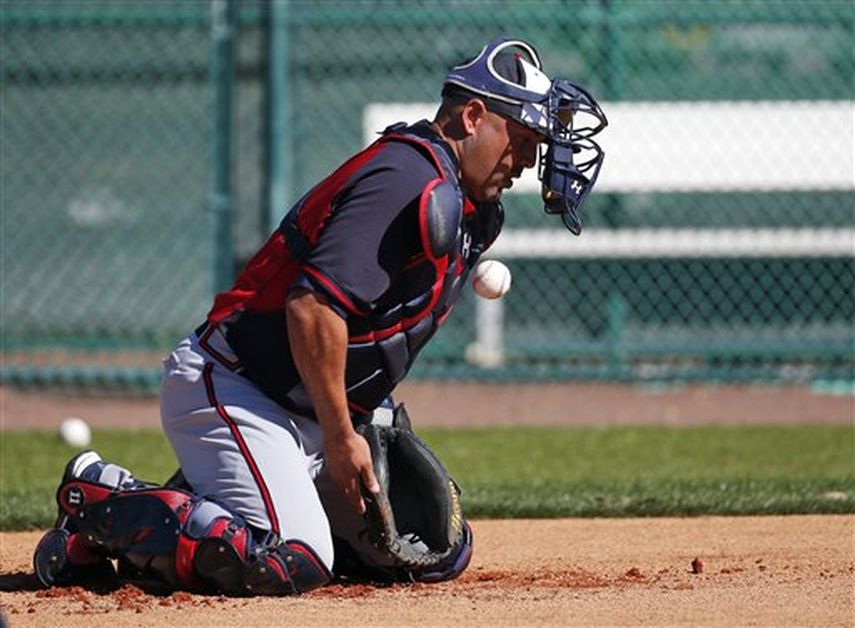 El receptor de los Bravos de Atlanta Gerald Laird bloquea la pelota mientras le rebota de frente durante los entrenamientos del martes 18 de febrero de 2014 en Kissimmee, Florida. Grandes Ligas dará a conocer el lunes sus nuevas reglas sobre los choque