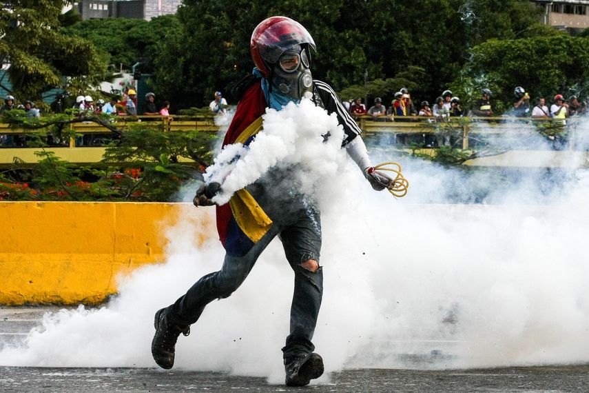 Un manifestante opositor venezolano se enfrenta a la represión de las fuerzas de seguridad del régimen de Nicolás Maduro en medio de bombas lacrimógenas.