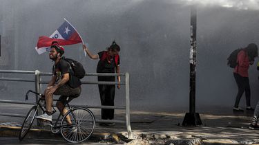 Un polic&iacute;a roc&iacute;a agua a manifestantes contra el gobierno durante enfrentamientos en Santiago de Chile el jueves 7 de noviembre de 2019.&nbsp;