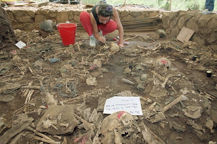 En esta foto de archivo del 23 de octubre de 1992, la antrop&oacute;loga forense Claudia Bernard, de Argentina, limpia tierra de restos humanos en El Mozote, El Salvador.&nbsp;