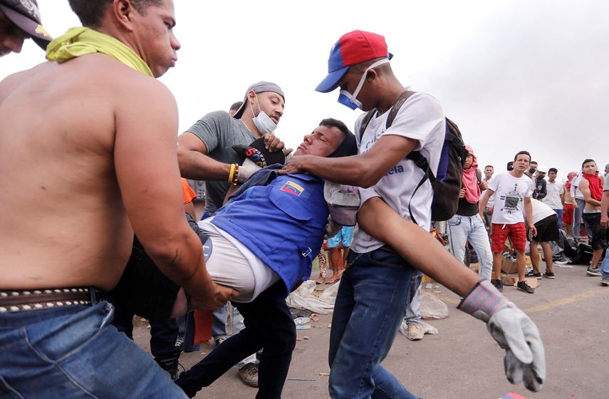 Manifestantes socorren a un hombre herido este sábado en los enfrentamientos entre civiles y militares en la frontera venezolana con Brasil y Colombia, ante la negativa del régimen de Maduro de dejar entrar la ayuda humanitaria.