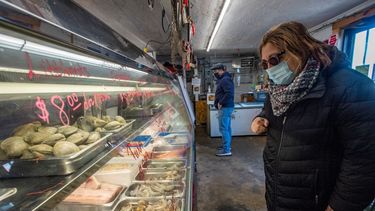 Una clienta observa los precios y productos del mar en un pequeño mercado.