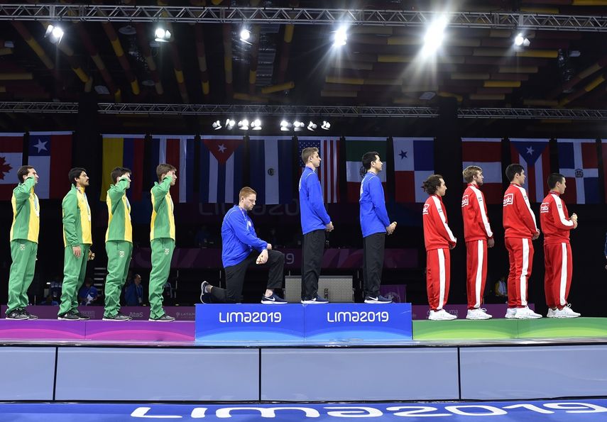 E estadounidense Race Imboden, del equipo de esgrima, se arrodilla en señal de protesta durante la ceremonia en que él y sus compañeros recibieron la medalla de oro en florete por equipos en los Juegos Panamericanos de Lima 2019.&nbsp;