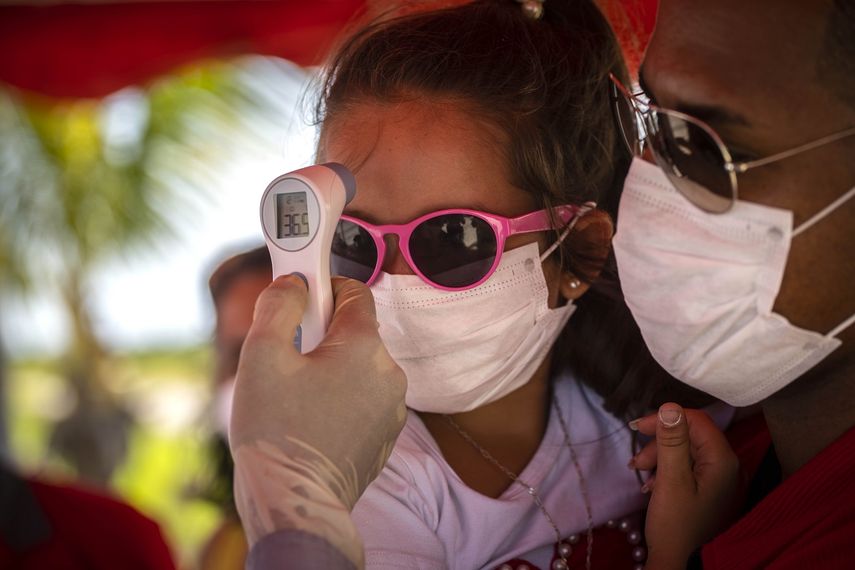 A una ni&ntilde;a con mascarilla para protegerse del nuevo coronavirus le toman la temperatura en un ret&eacute;n policial en la entrada de la provincia de La Habana, Cuba, en esta fotograf&iacute;a de archivo del lunes 10 de agosto de 2020.&nbsp;