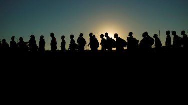Migrantes que cruzaron el río Bravo e ingresaron a Estados Unidos desde México se forman para ser procesados por la Oficina de Aduanas y Protección Fronteriza de Estados Unidos, el 23 de septiembre de 2023, en Eagle Pass, Texas. 